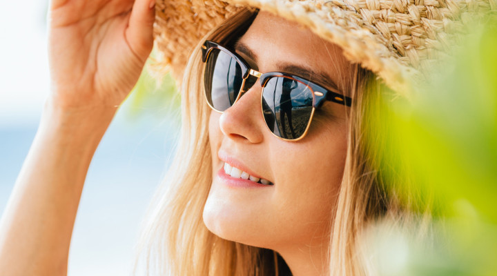 Woman in Sunglasses and Straw Hat on the Beach in Summer - Best Hats for Spring and Summer Travel
